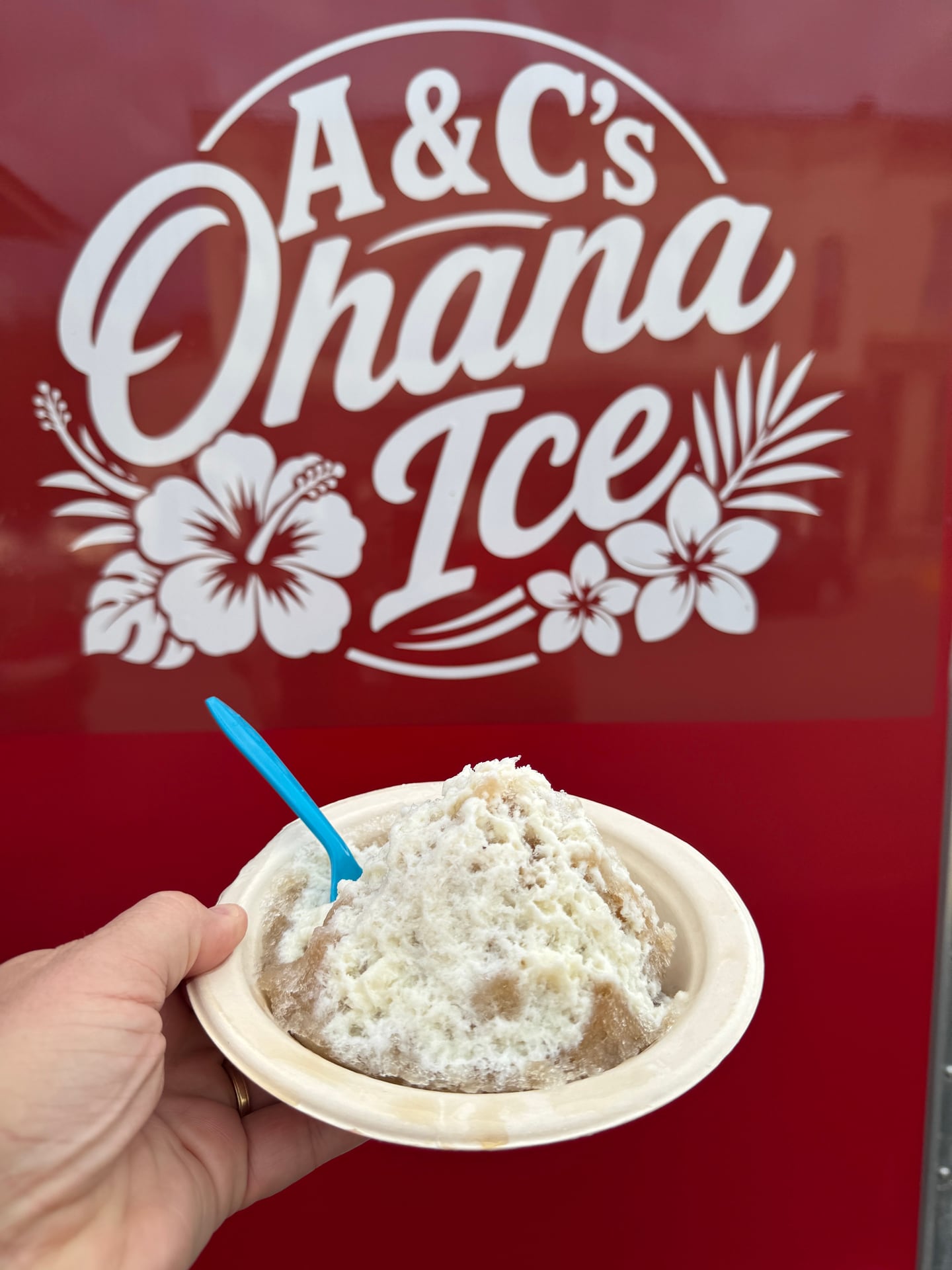 A bowl of Rudyhana shaved ice held in front of the A and C's Ohana Ice trailer logo